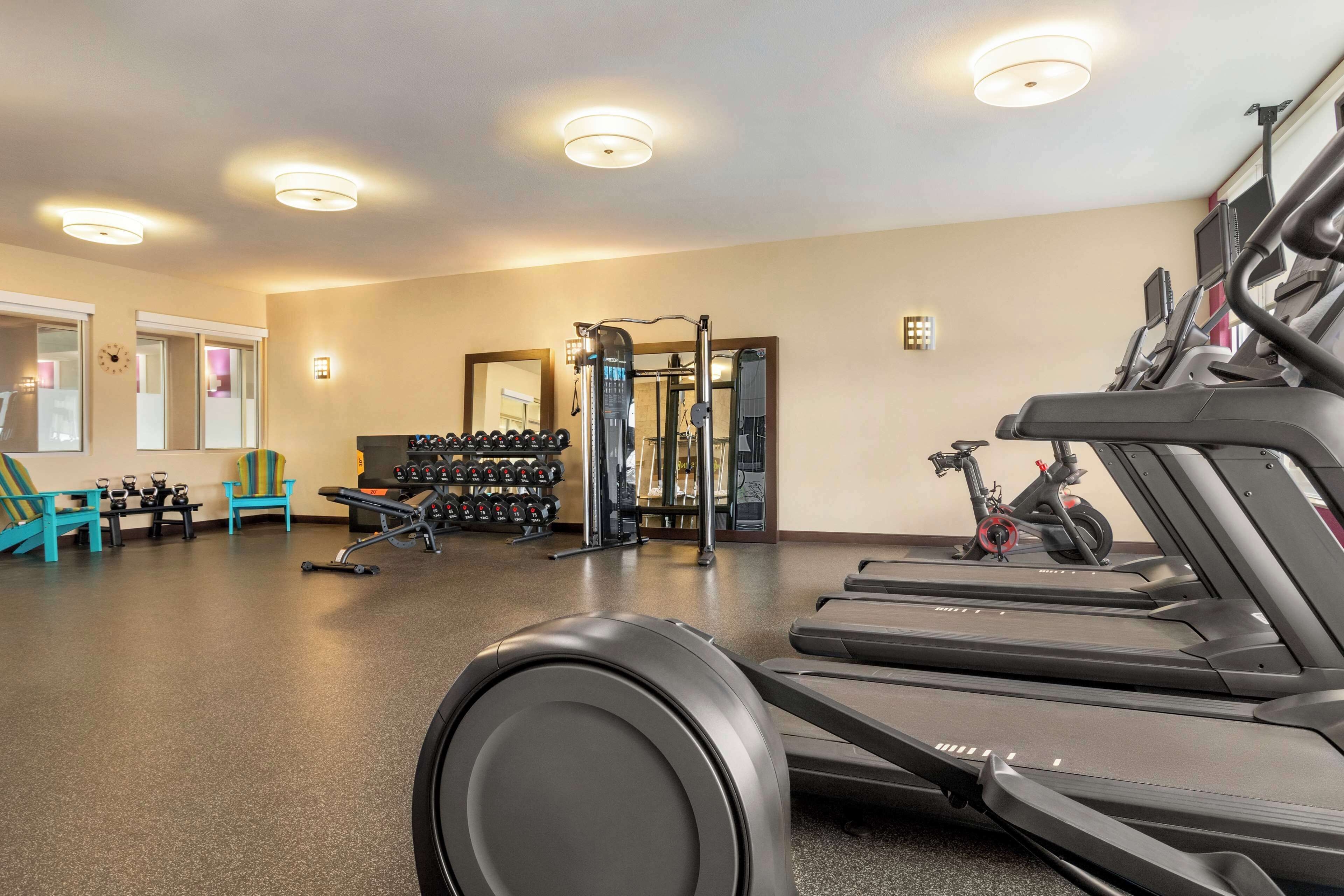 Een fitnessruimte met loopbanden, krachtapparaten en losse gewichten.