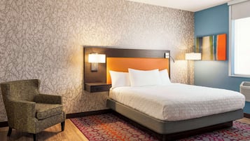 Une chambre d’hôtel avec un grand lit, une chaise, un mur décoré de motifs et une fenêtre avec des stores.