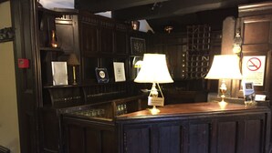 A bar area with wooden paneling, two lamps, and a display of various items including a sign with a price tag. - String of Horses (Brampton)