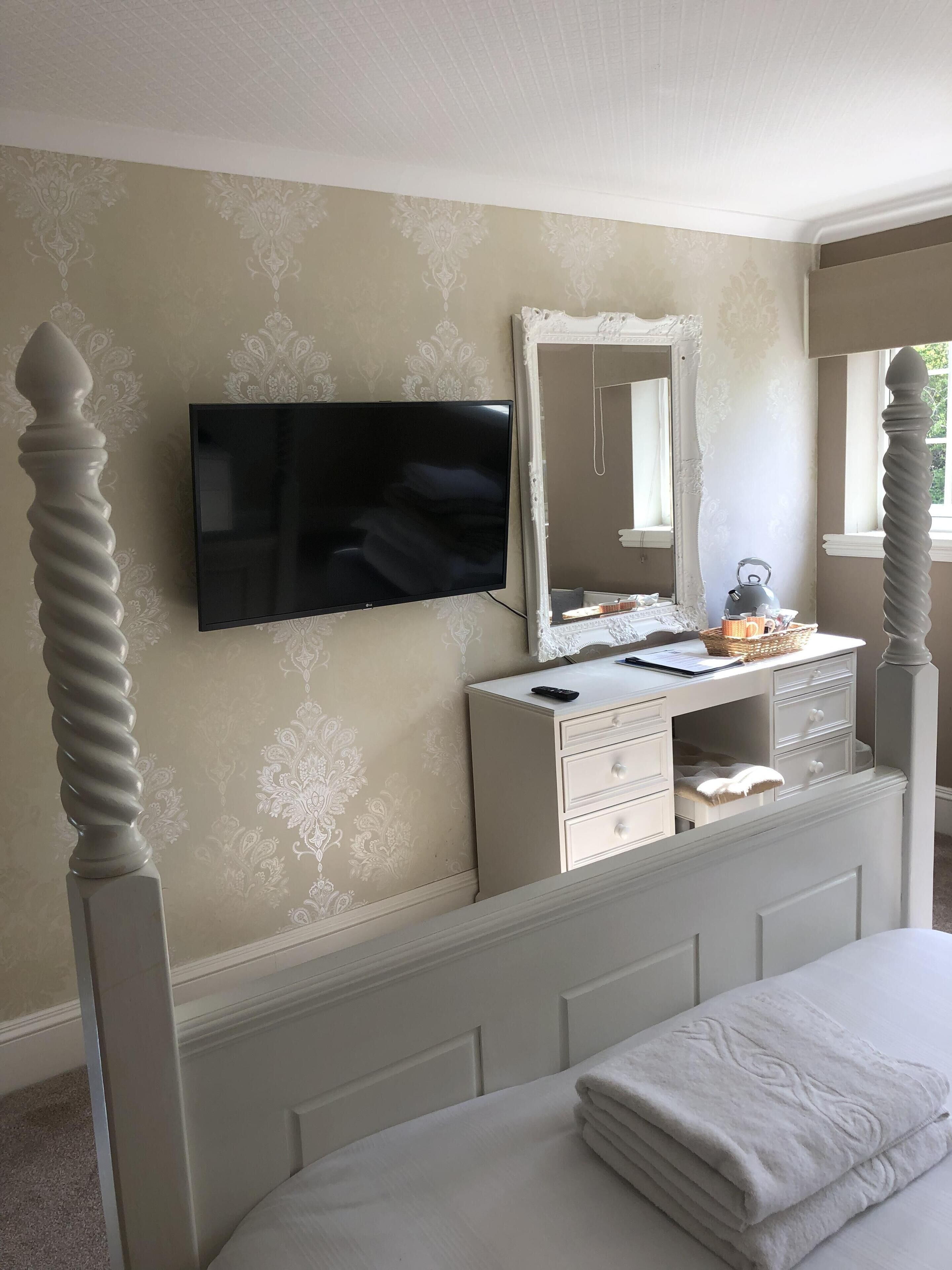 Une chambre à coucher avec un lit, une commode, un miroir et un téléviseur.