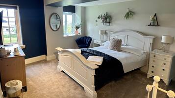 A bedroom with a bed, bedside tables, a chair, a window, a mirror, and a small desk with a lamp.