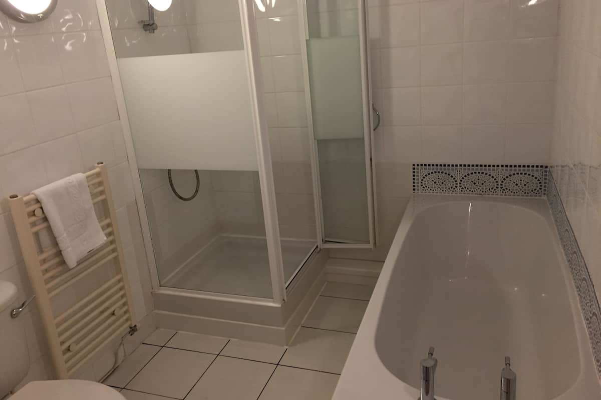 Ett badrum med badkar, duschkabin, toalett och handduksställ.