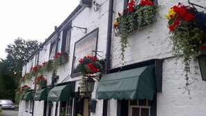 A traditional white building with green awnings, a sign reading "Story of Horses Restaurant," and flower boxes on the windowsills. - String of Horses (Brampton)