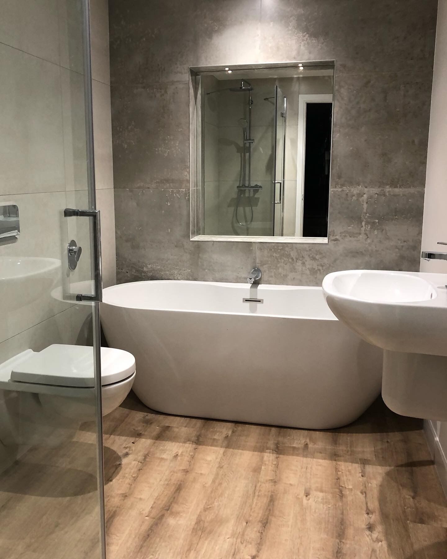 Une salle de bain moderne avec une baignoire sur pieds, une douche à parois de verre et deux lavabos.