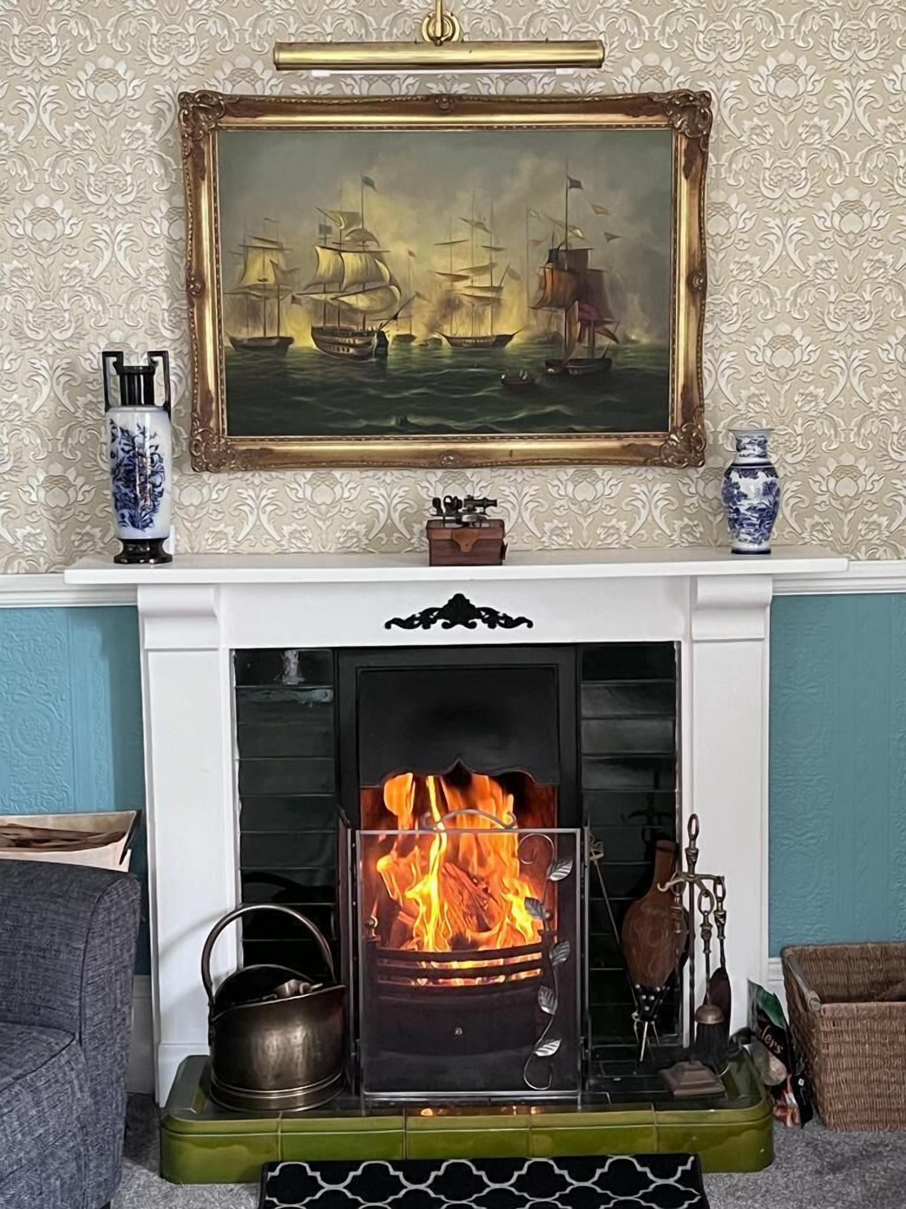 A fireplace with a painting above it, a vase, and a decorative box.