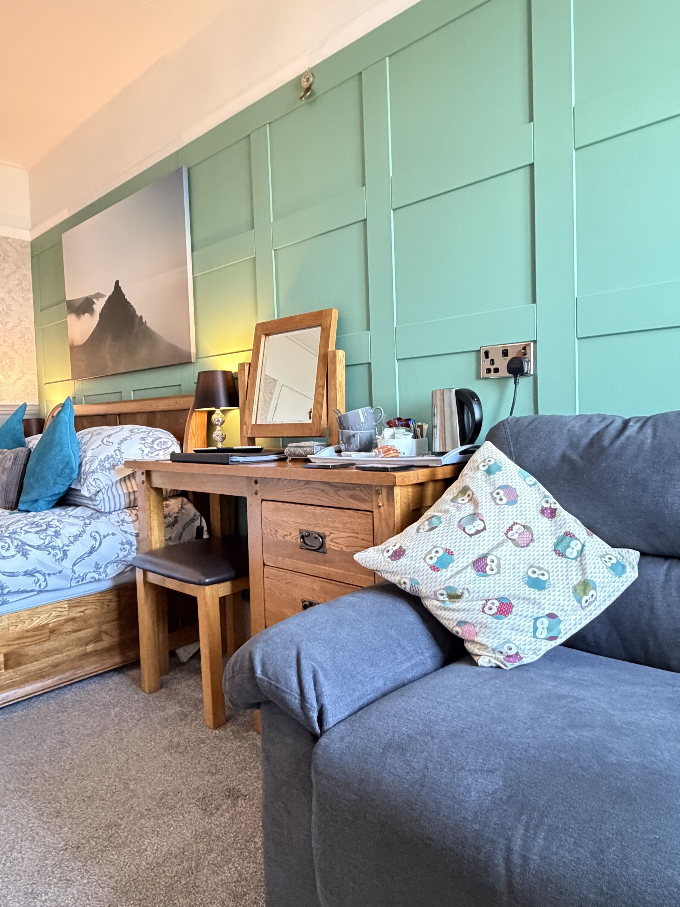 A bedroom with a bed, a desk, a chair, and a sofa.