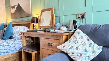 A bedroom with a bed, a desk, a chair, and a sofa.