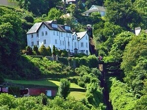 A large, white, multi-story house surrounded by lush greenery, likely a private residence or estate. - The North Cliff Hotel (Lynton)