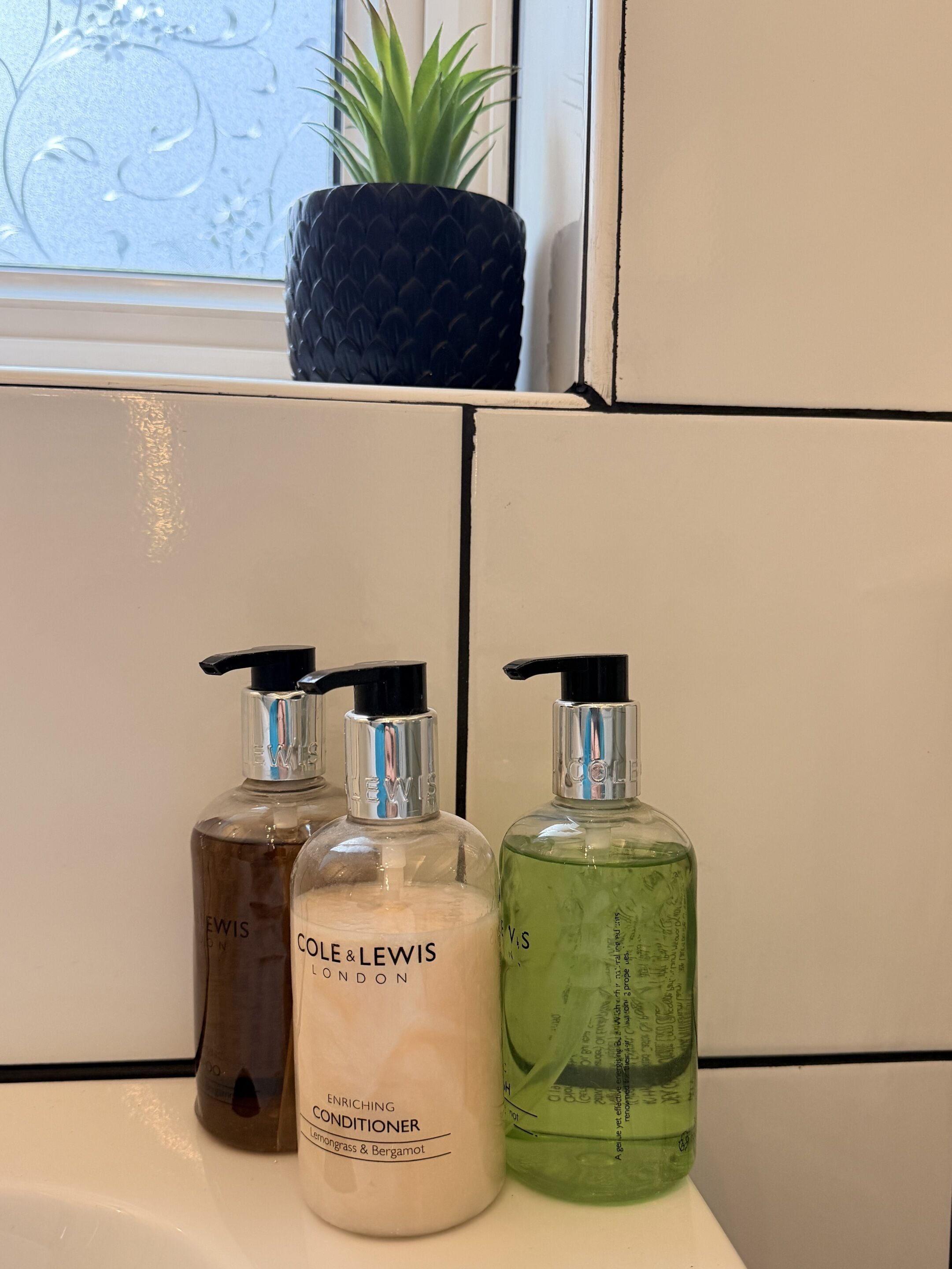 Tres botellas de acondicionador sobre una encimera de baño.