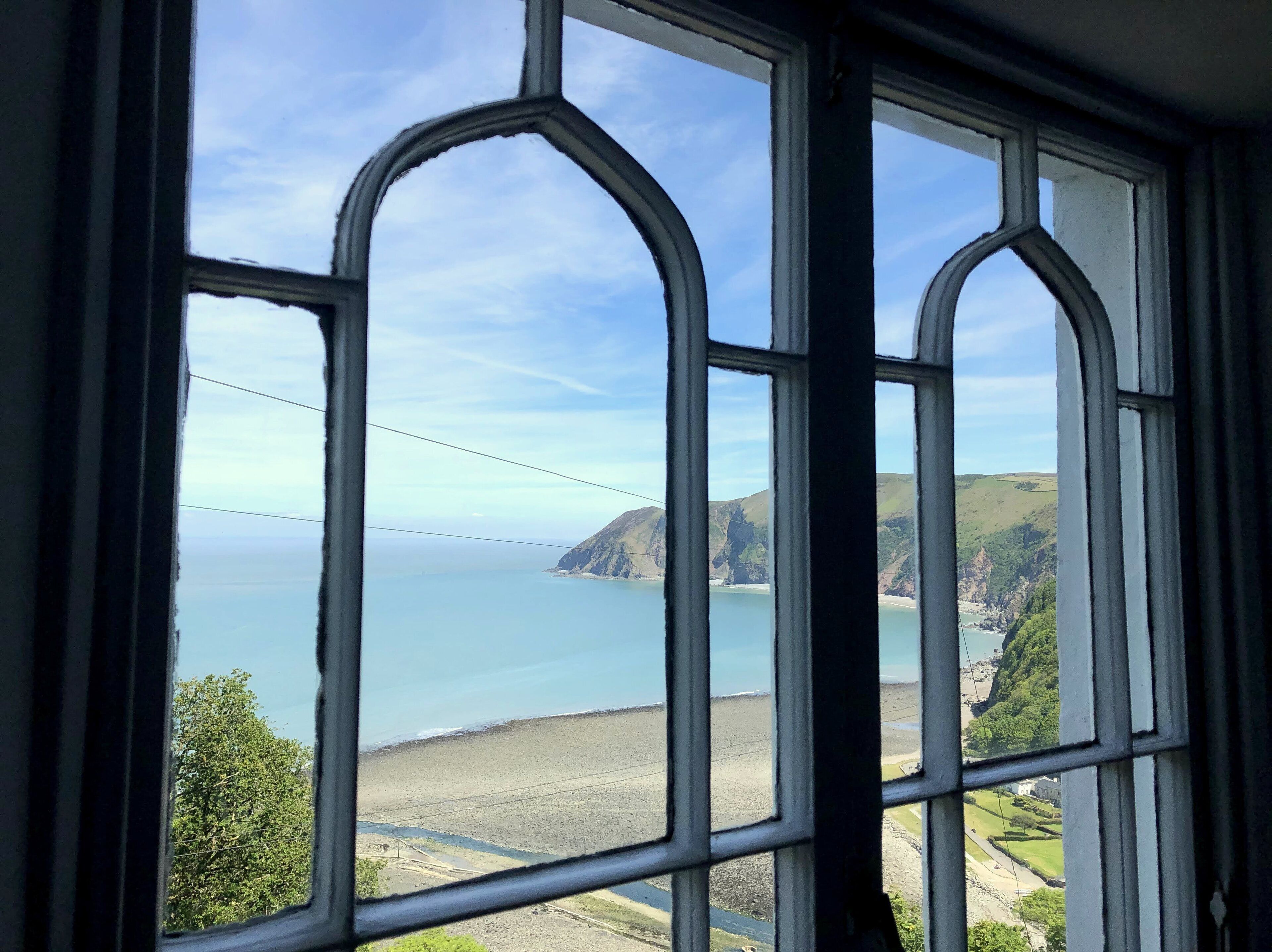 Une vue à travers une fenêtre, avec un ciel dégagé et un paysage côtier.