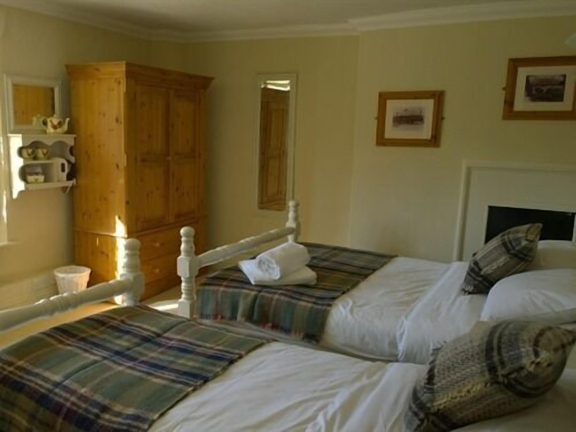 A bedroom with two beds, a wooden wardrobe, a mirror, and a framed picture on the wall.