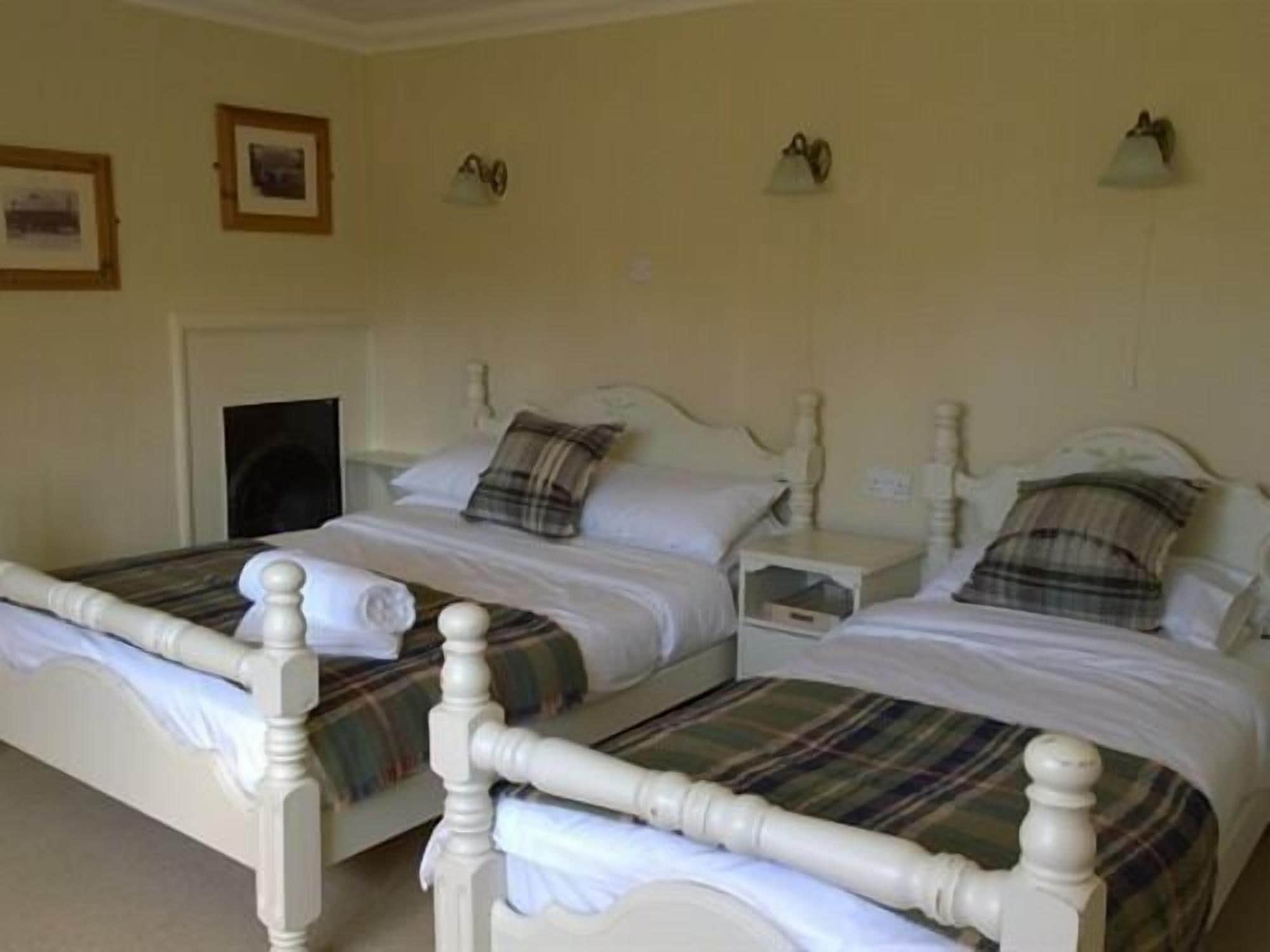 A double bed with a wooden frame and white bedding, two bedside tables with lamps, and a door in the background.
