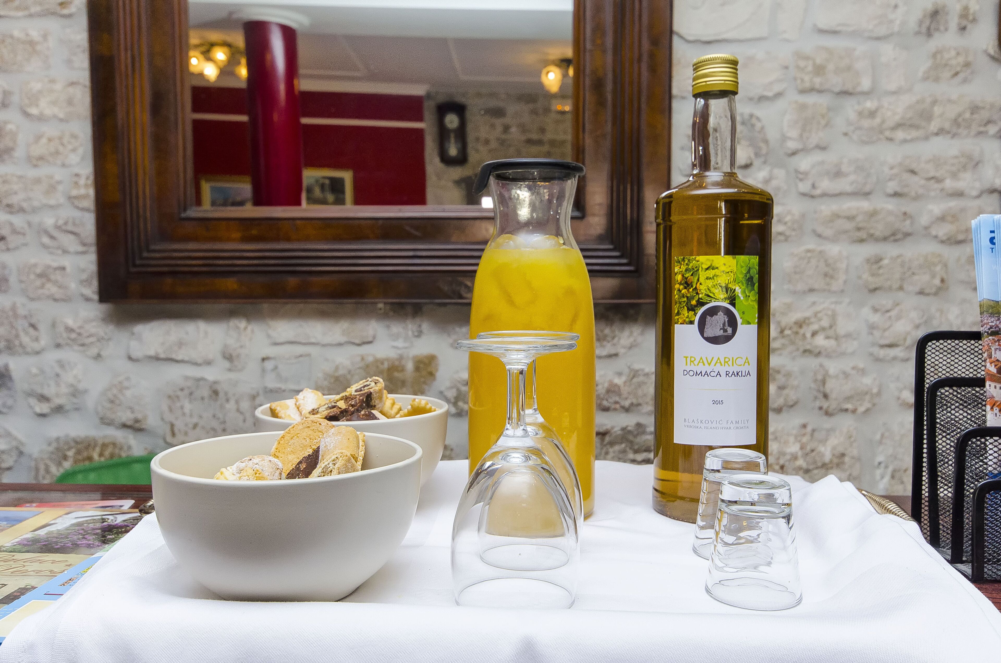 A table with a bowl of food, a wine glass, a bottle of wine, and a bottle of orange juice.