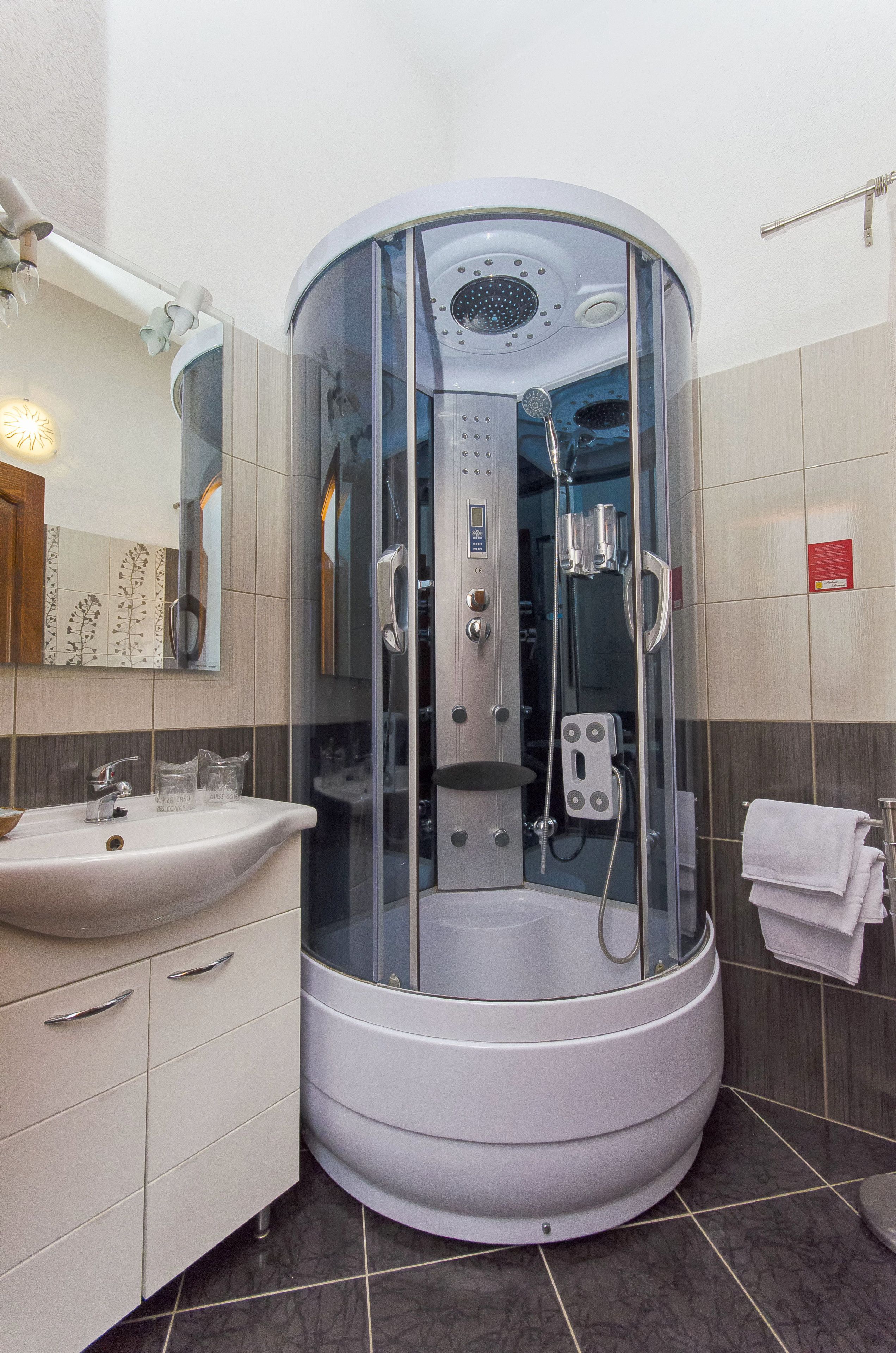 A modern bathroom with a glass-enclosed shower, a sink, and a mirror.