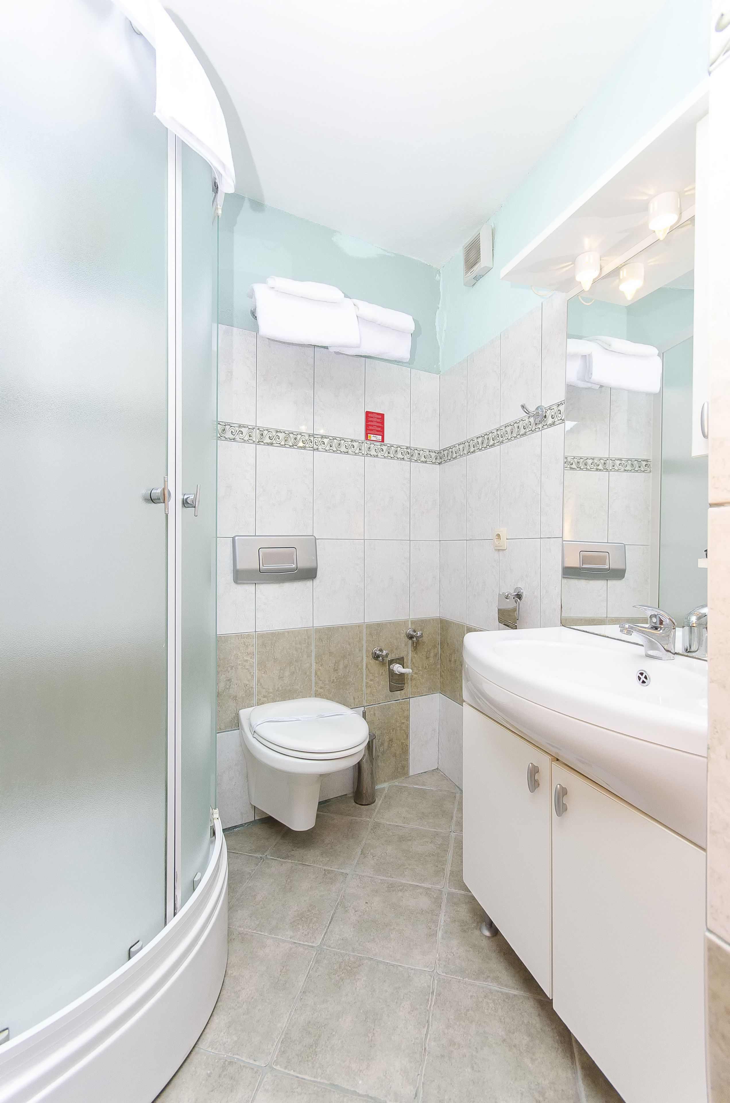 Un baño con ducha de vidrio, inodoro y lavabo con espejo.