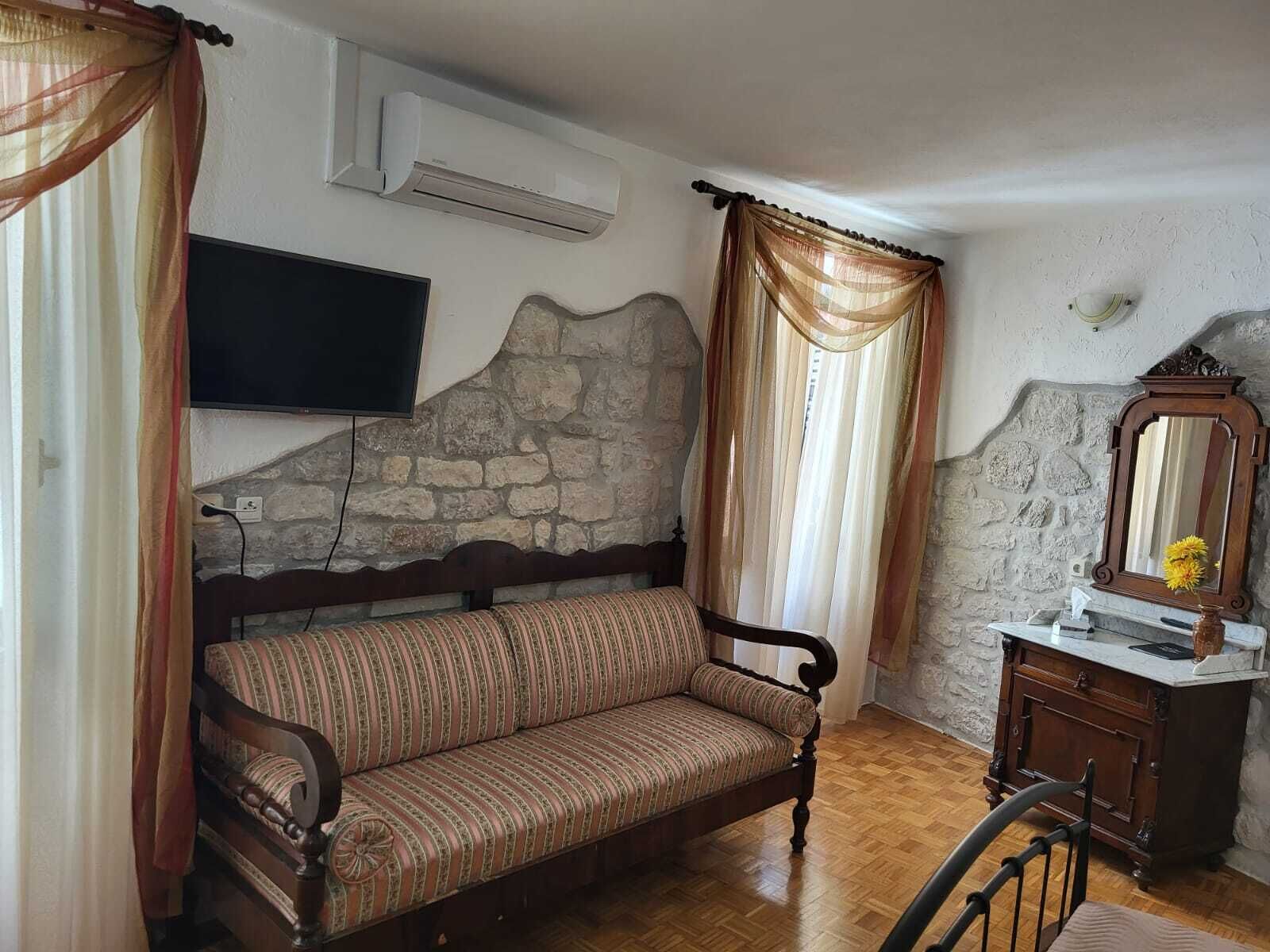 Una habitación acogedora con sofá de madera, pared de piedra, televisor de pantalla plana y cómoda de madera con espejo.