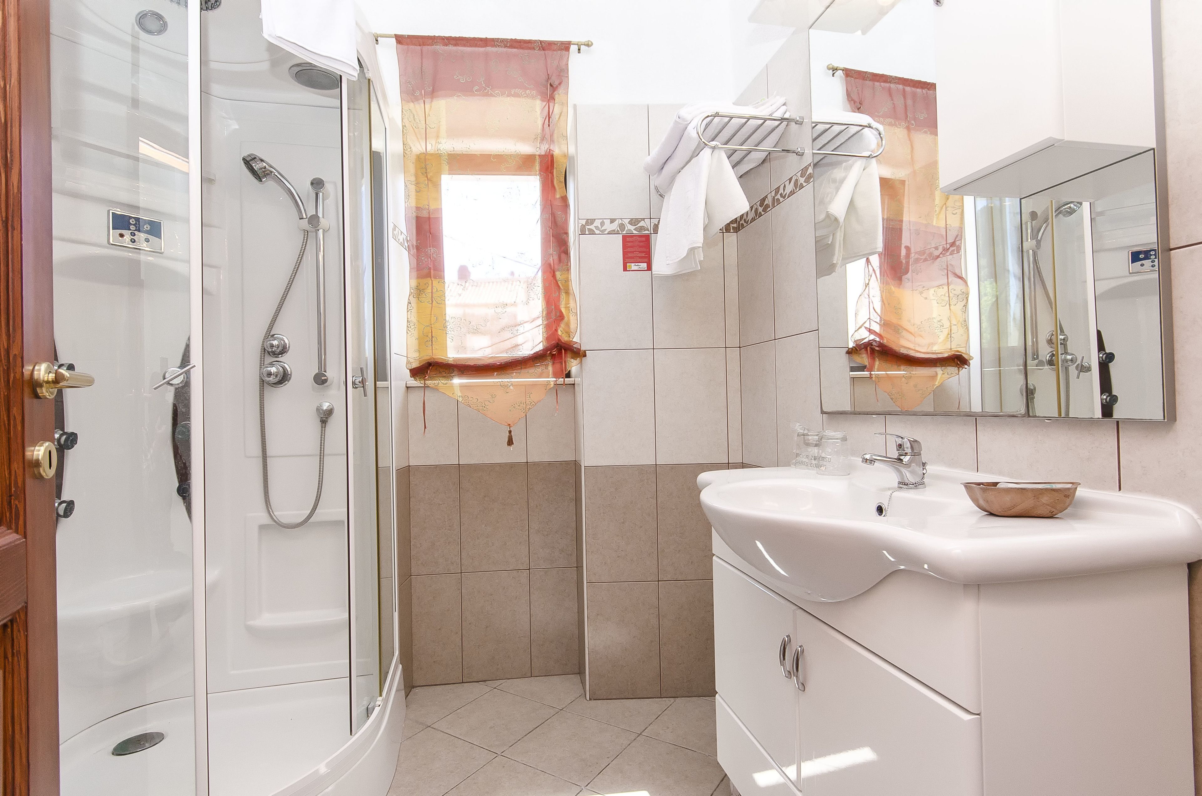 A bathroom with a glass-enclosed shower, a white sink with a bowl, and a mirror with a towel rack.