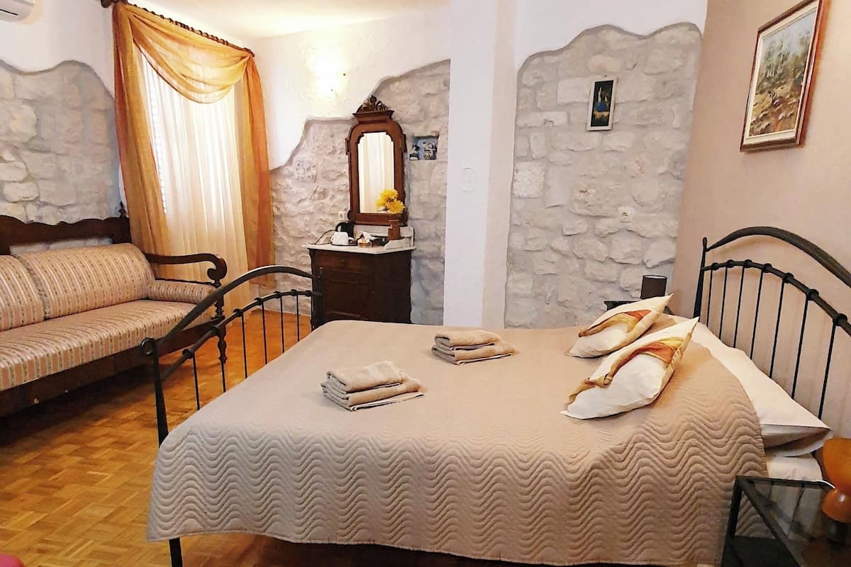 Un dormitorio con cama, sofá, espejo y pared de piedra.