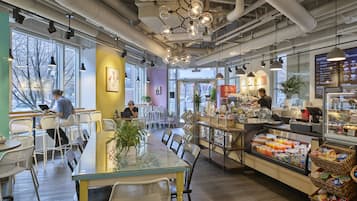 Enjoy a meal or work session at this stylish café with a central table, counter area, and comfortable seating.