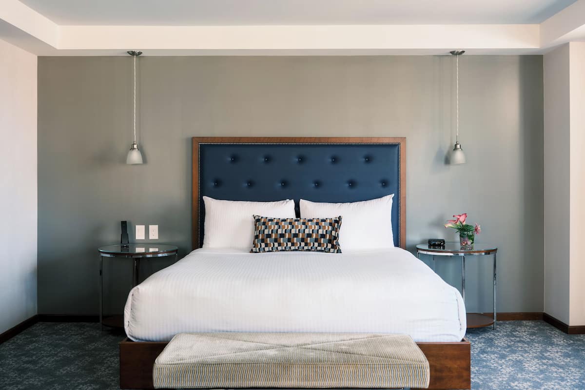 A neatly arranged hotel room with a large bed, bedside tables, and a bench.