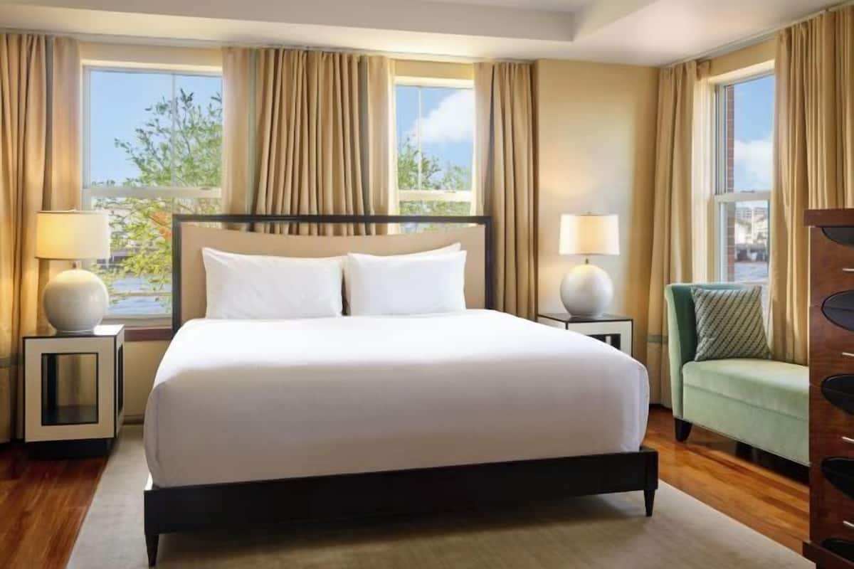 A hotel room with a large bed, two bedside tables, a chair, and a view of the outdoors.