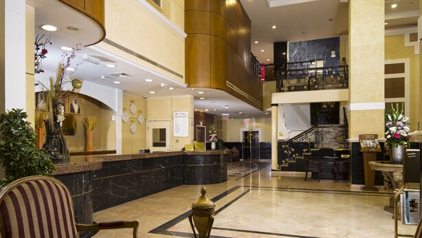 A spacious lobby with a high ceiling, a reception desk, and a staircase leading to an upper level. - Baisan International Hotel Bahrain (Manama)
