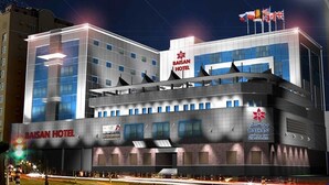 A modern hotel building with multiple floors, a prominent sign reading "BASAN HOTEL," and flags on the roof. - Baisan International Hotel Bahrain (Manama)