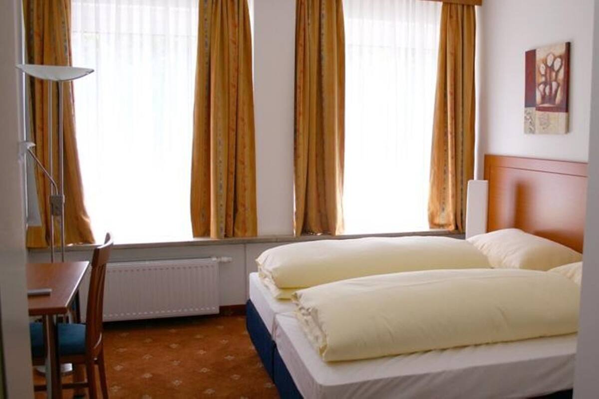 A hotel room with a bed, a desk, and a chair.