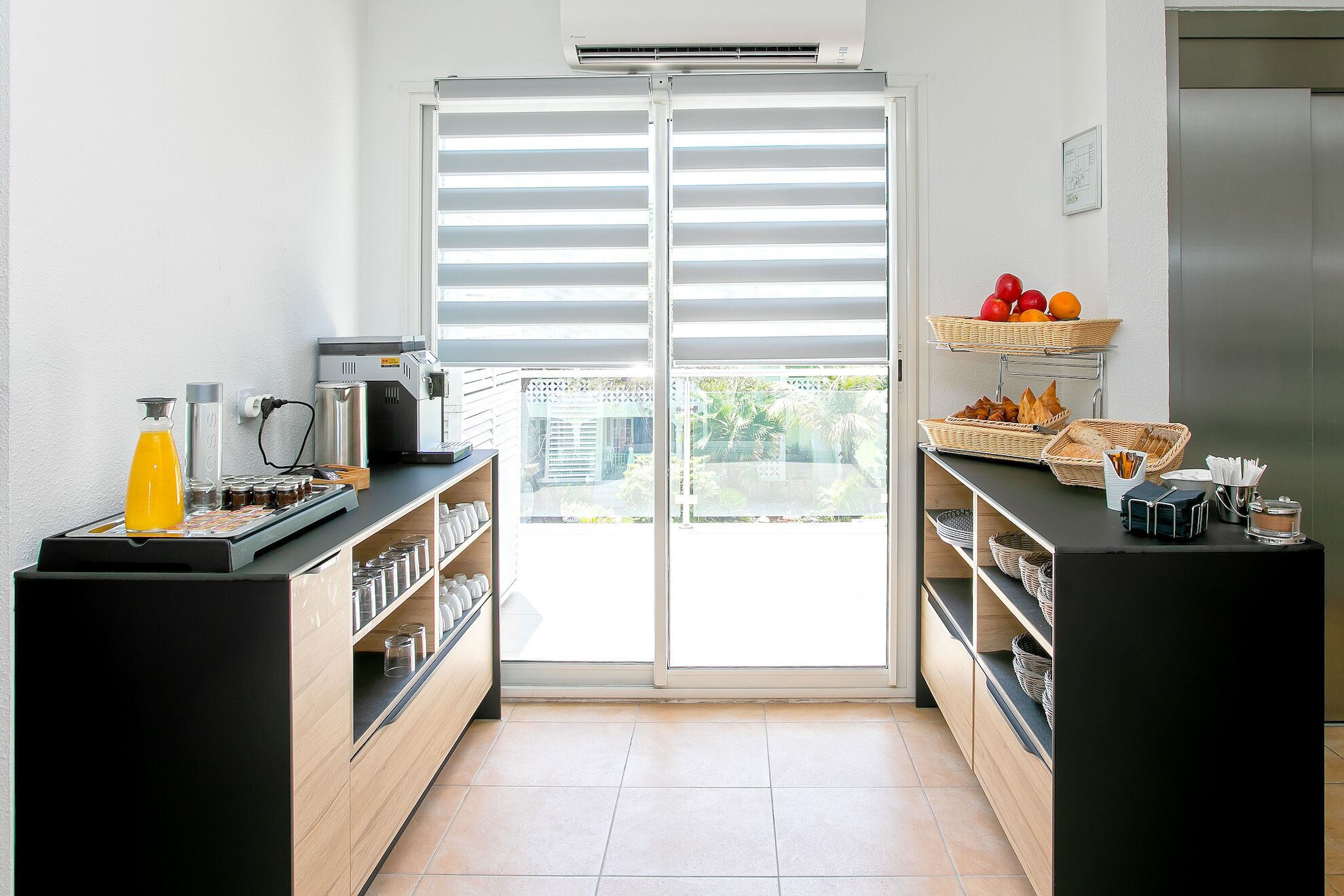 A modern kitchen with a coffee machine, a fruit basket, and a bread basket on a counter.
