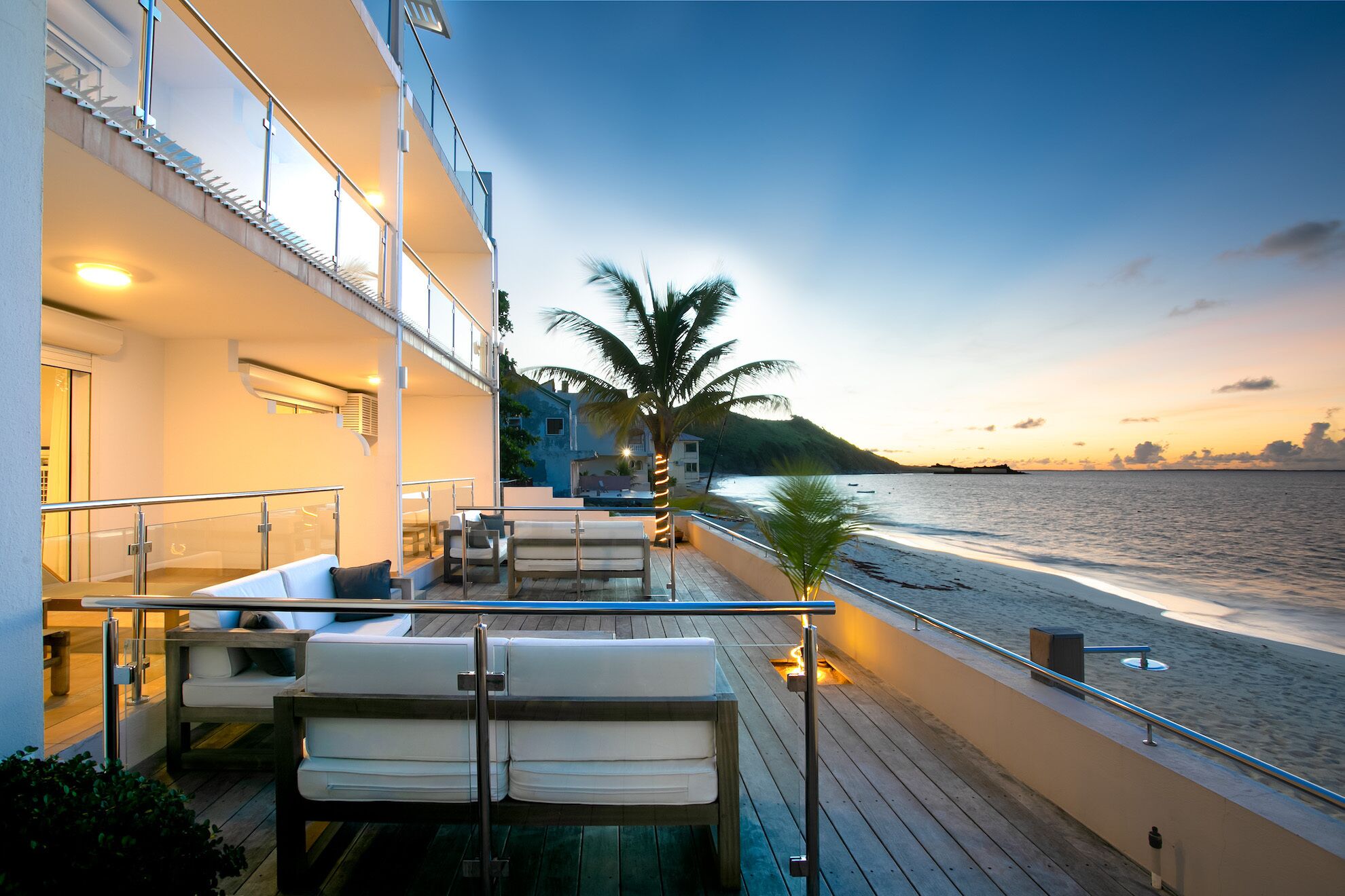 Uma varanda com vista para a praia e oceano ao pôr do sol.