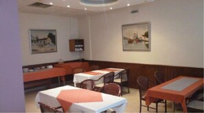 A restaurant with tables and chairs, a counter, and wall-mounted paintings.
