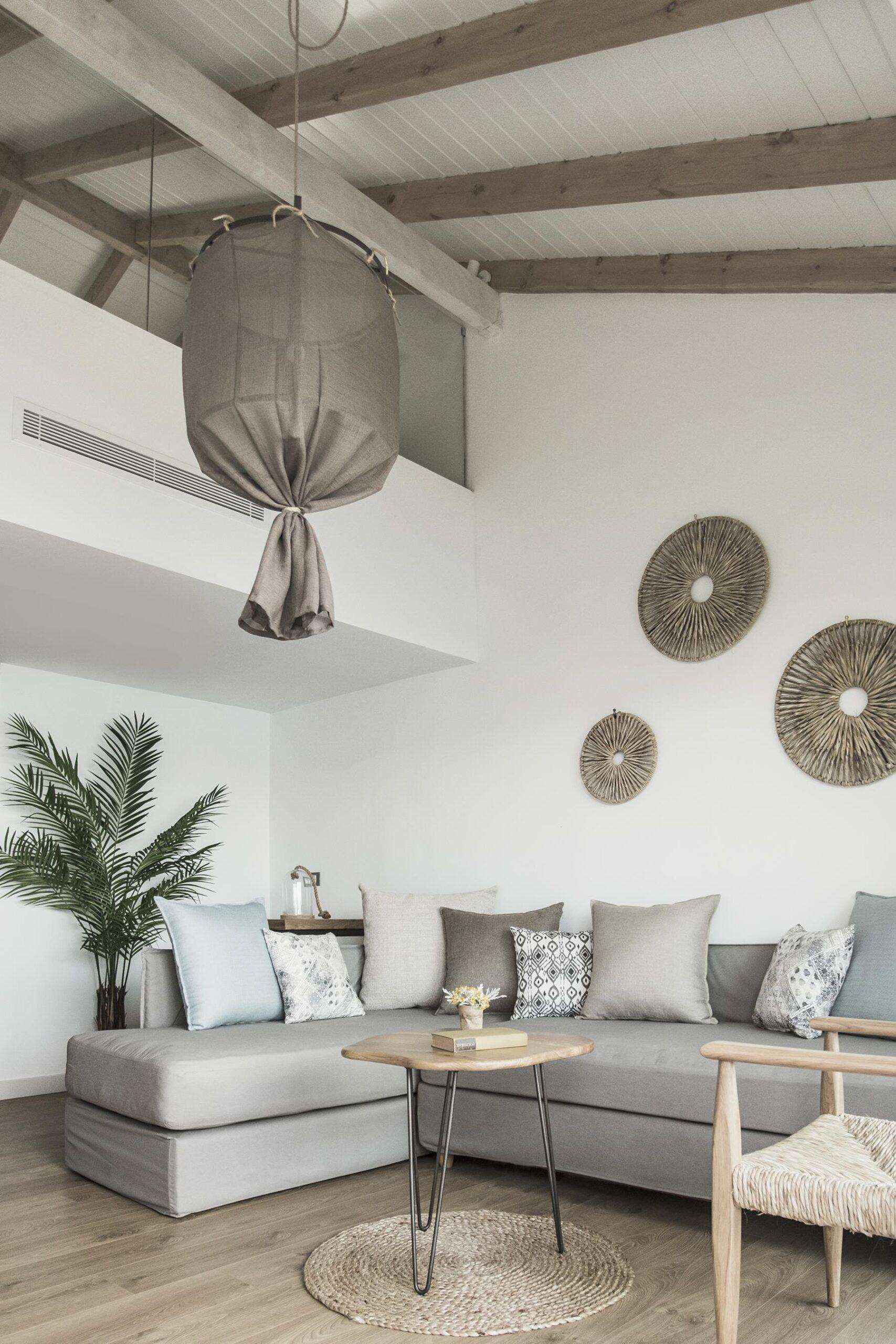 Ein modernes Wohnzimmer mit grauem Sofa, einem runden Couchtisch und einer Pendelleuchte.