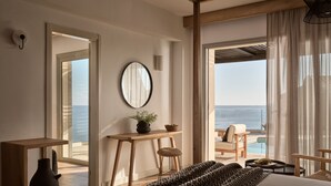 A modern hotel room with a large bed, a wooden desk, a mirror, and a view of the sea. - Seaside A Lifestyle Resort All Inclusive (Malevizi)