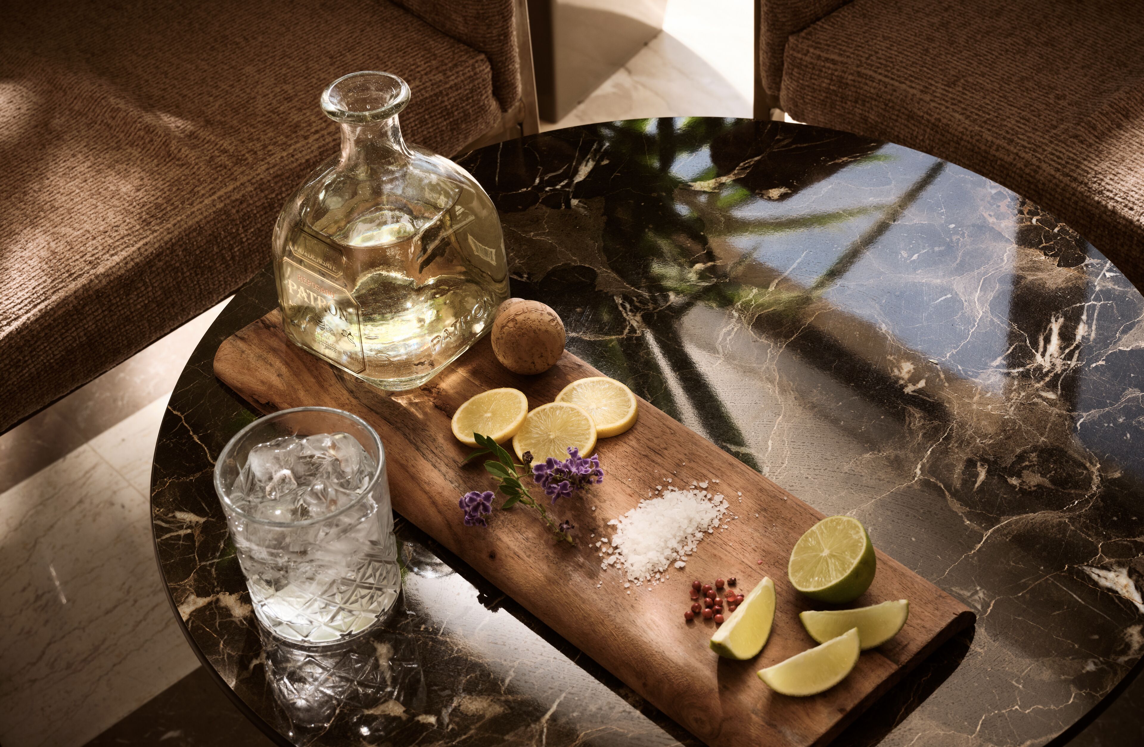 A table with a bottle of water, a glass of water, lemon slices, a cork, and some herbs.