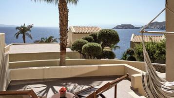 Una terraza con una hamaca, una mesita con un florero y vista al mar.