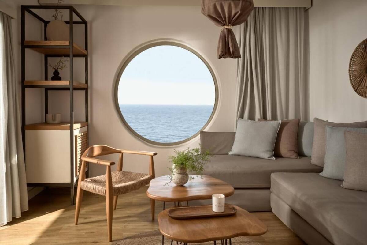 A cozy room with a round window, a wooden chair, a sofa, and a small table with a plant.