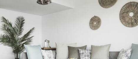 Un salon moderne avec un canapé gris, une table basse ronde et un luminaire suspendu.