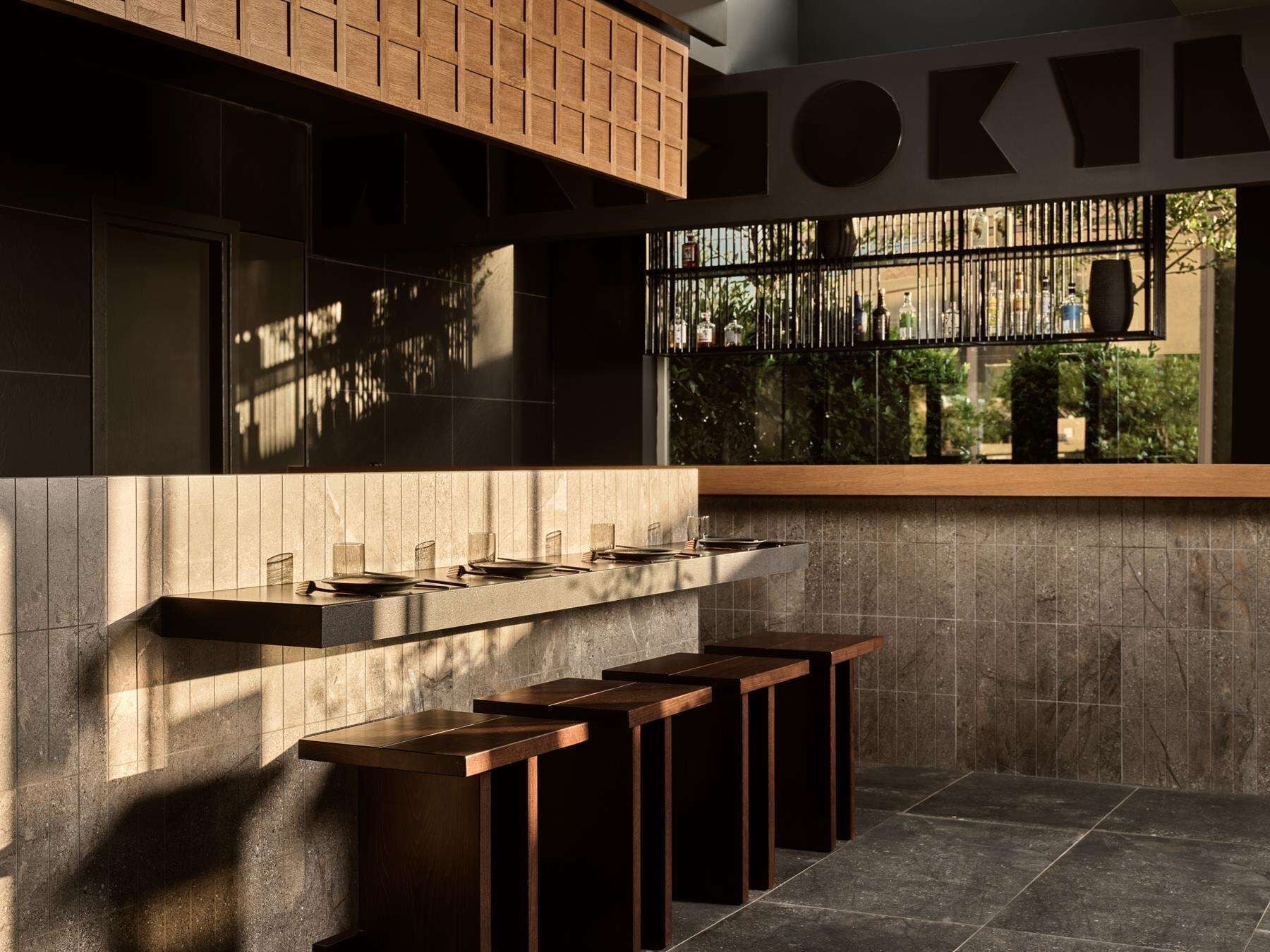 Cozinha moderna com espaço de bar embutido, grandes janelas e vista para o verde lá fora.