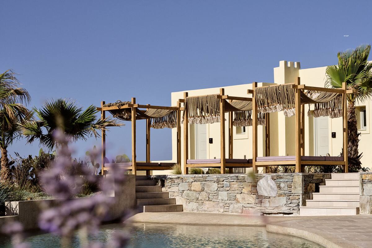 A resort with a pool, wooden cabanas, and stone steps leading to the pool area.