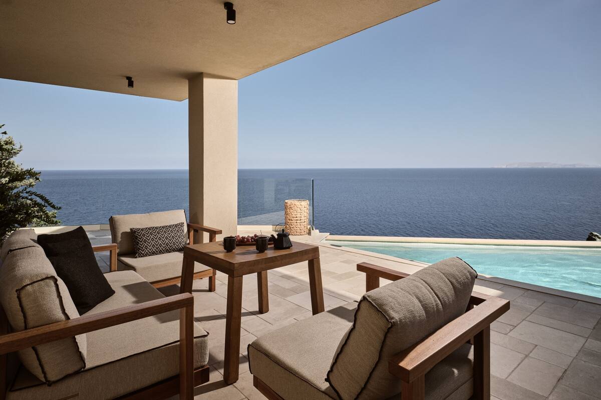 A terrace with outdoor seating, a pool, and a view of the sea.