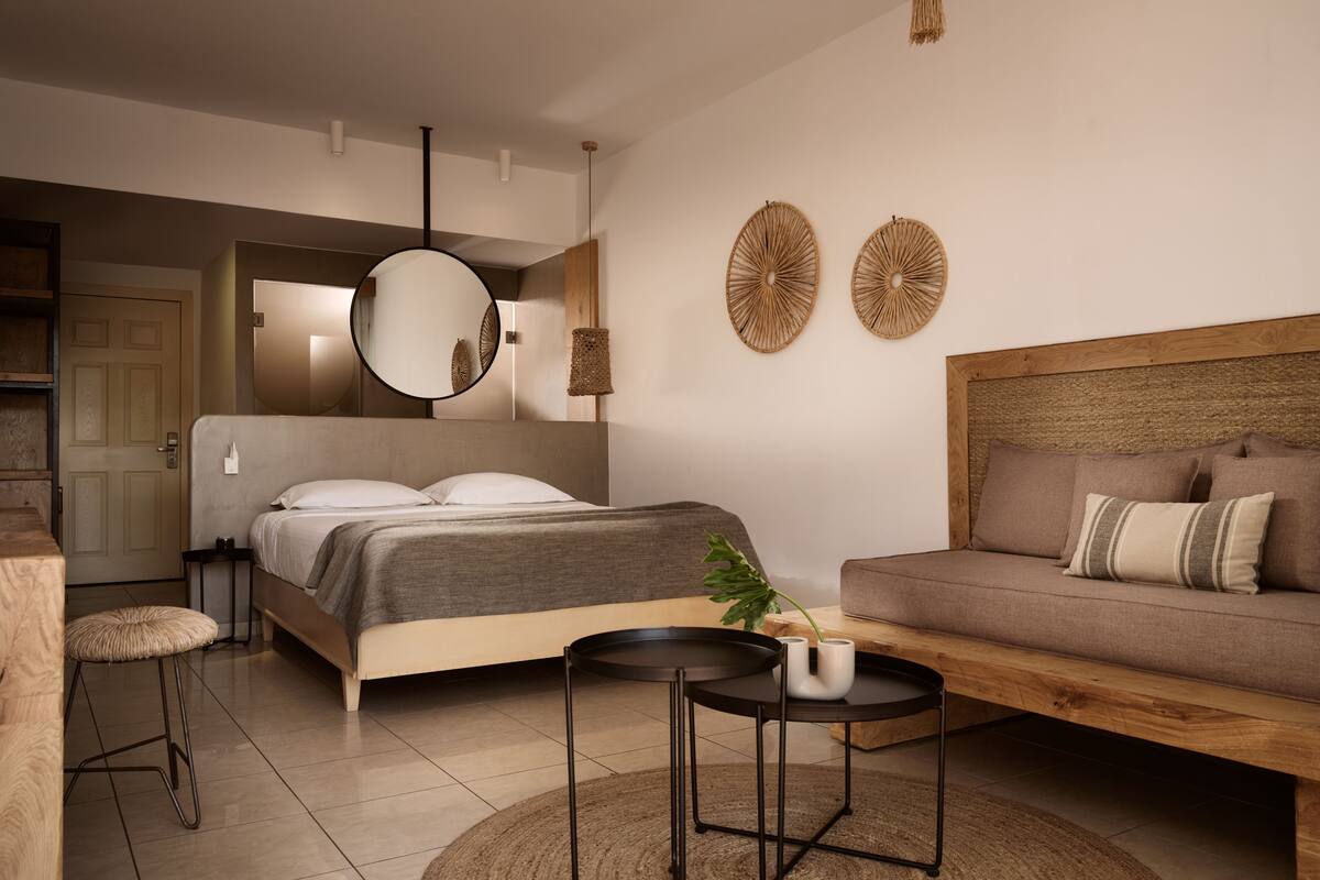 A modern bedroom with a bed, a sofa, a round coffee table, and a hanging light fixture.