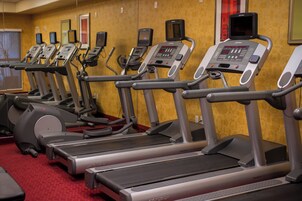 Varias caminadoras en un gimnasio de hotel, con paneles de control y espejos.