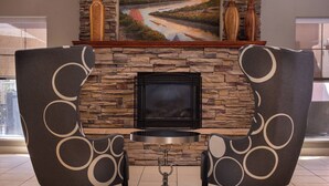 Una chimenea con detalles de piedra, dos sillones con diseños circulares y un cuadro sobre la chimenea.