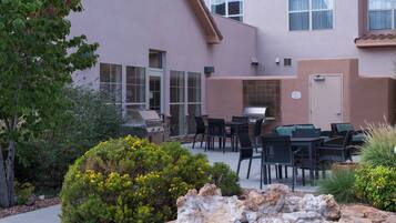 Un patio exterior con una parrilla, comedor y detalles de piedra.