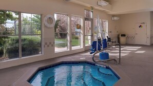 Piscina con un asiento de salvavidas, una escalera y vistas al exterior a través de amplias ventanas.