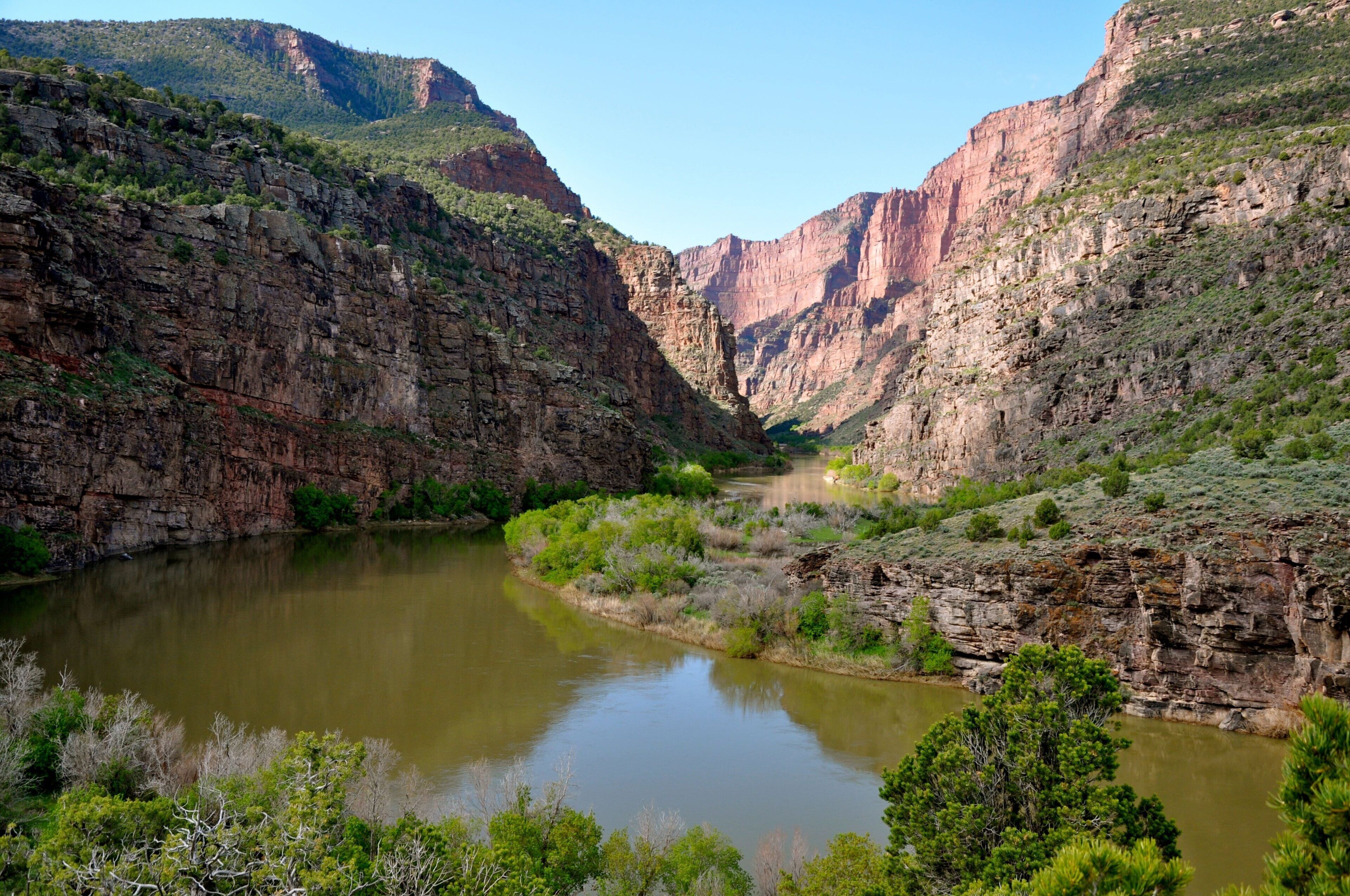 Um cânion com rio, penhascos rochosos e vegetação escassa.