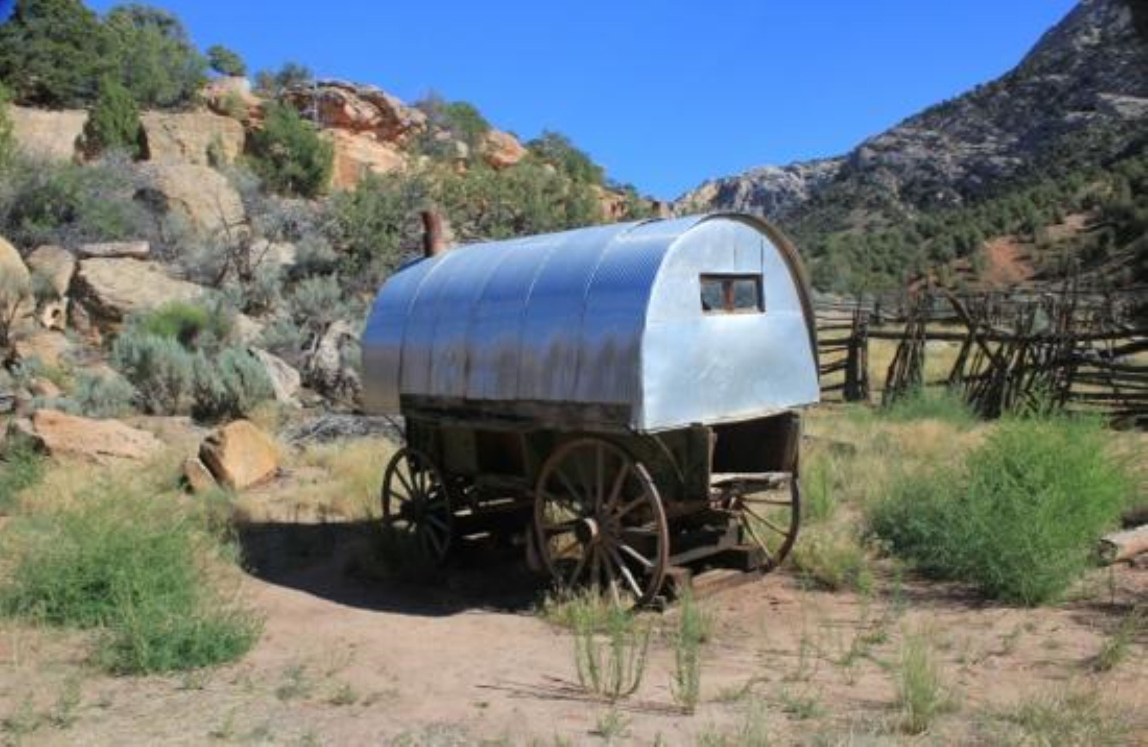 A covered wagon in a natural setting with a clear sky.