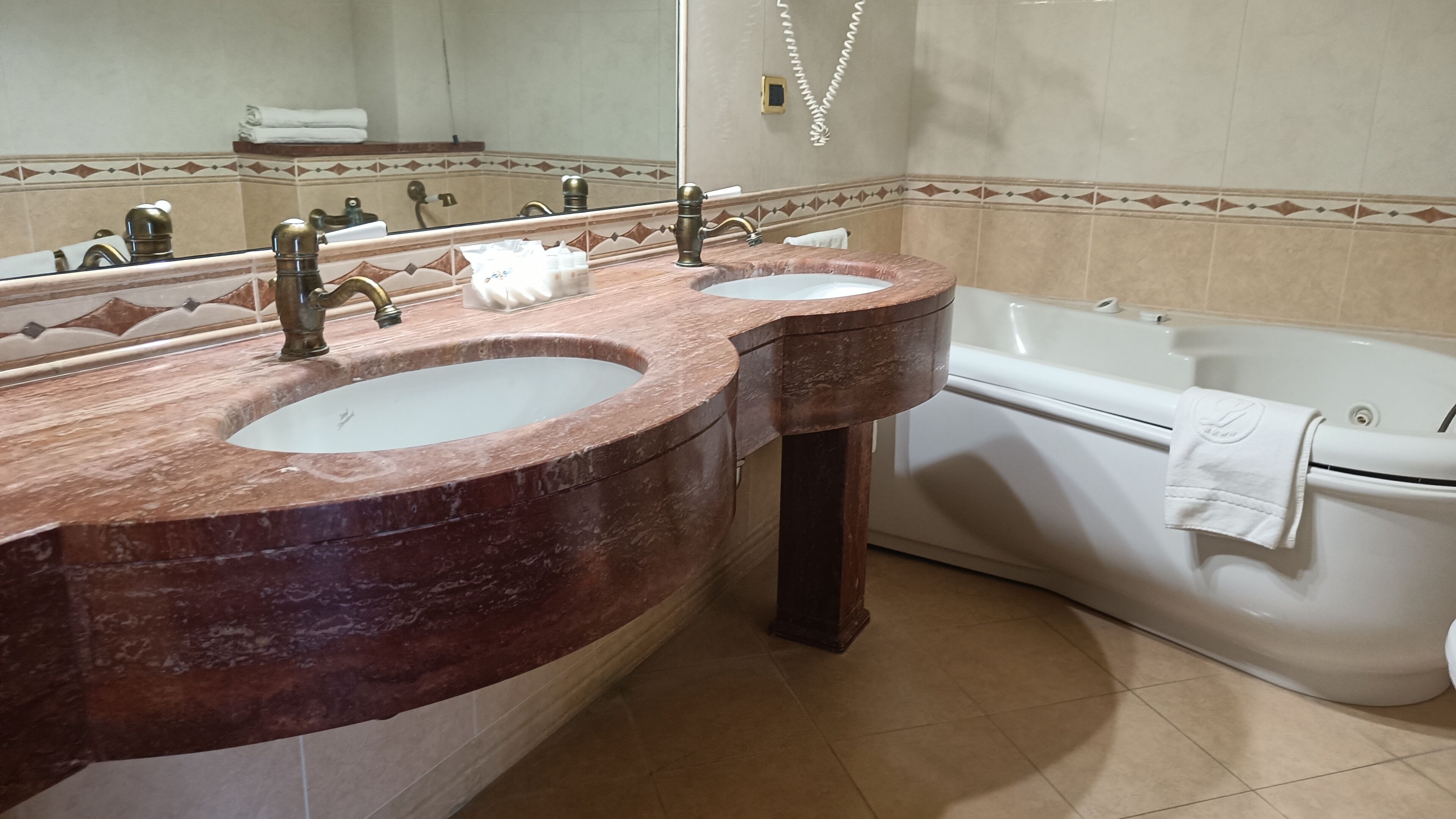 A bathroom with two sinks, a bathtub, and a large mirror.