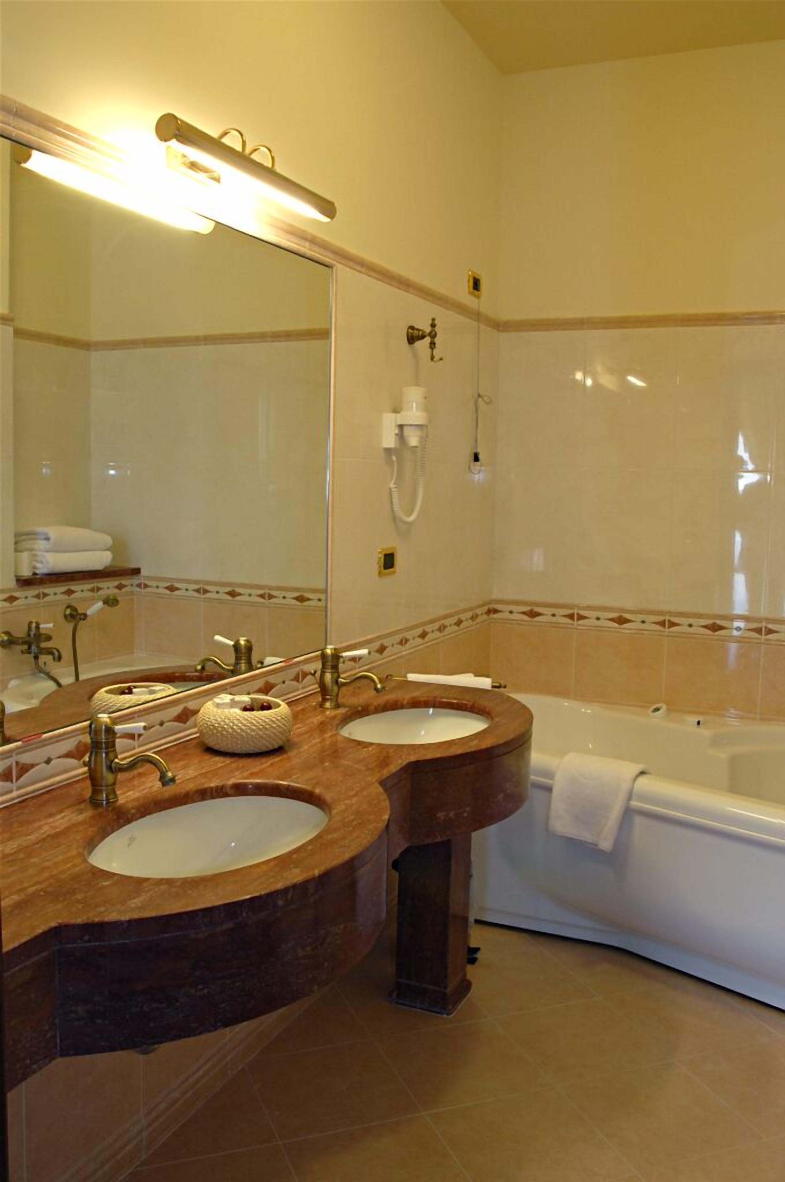 Ein Badezimmer mit zwei Waschbecken, einer Badewanne und einem großen Spiegel.
