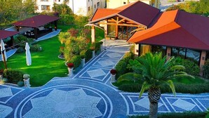 Une cour avec un sol carrelé à motifs, un espace de repos abrité et un bâtiment doté d’un toit rouge.